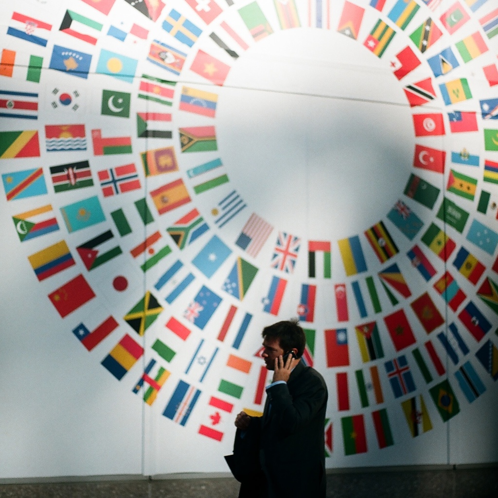 man walking in front of circular art with world flags