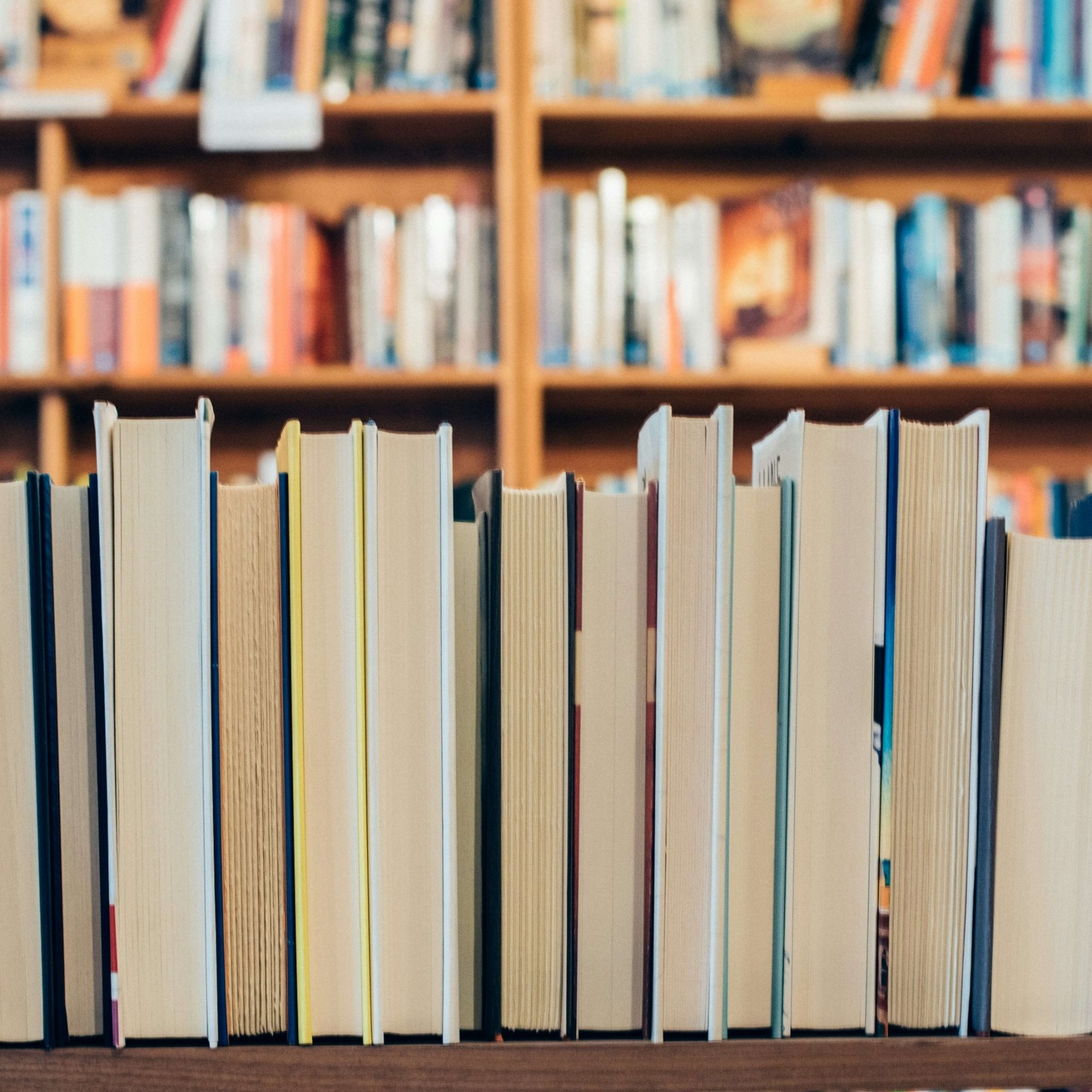 stack of books in front of bookshelves