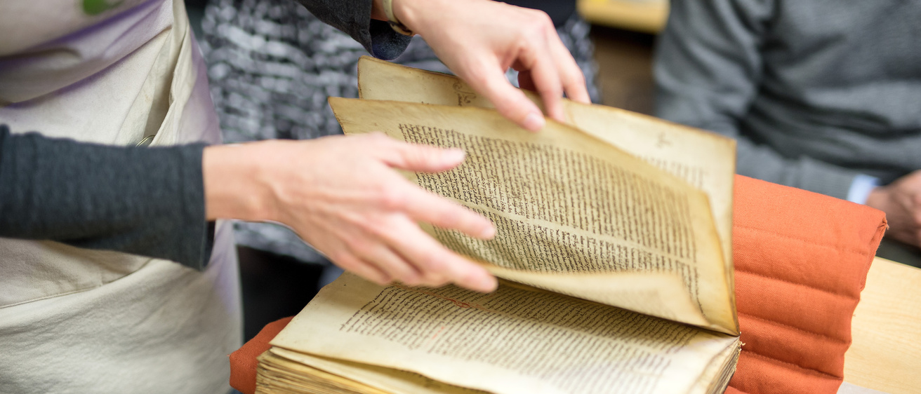 a person's hands hold a very old book and flip through its pages