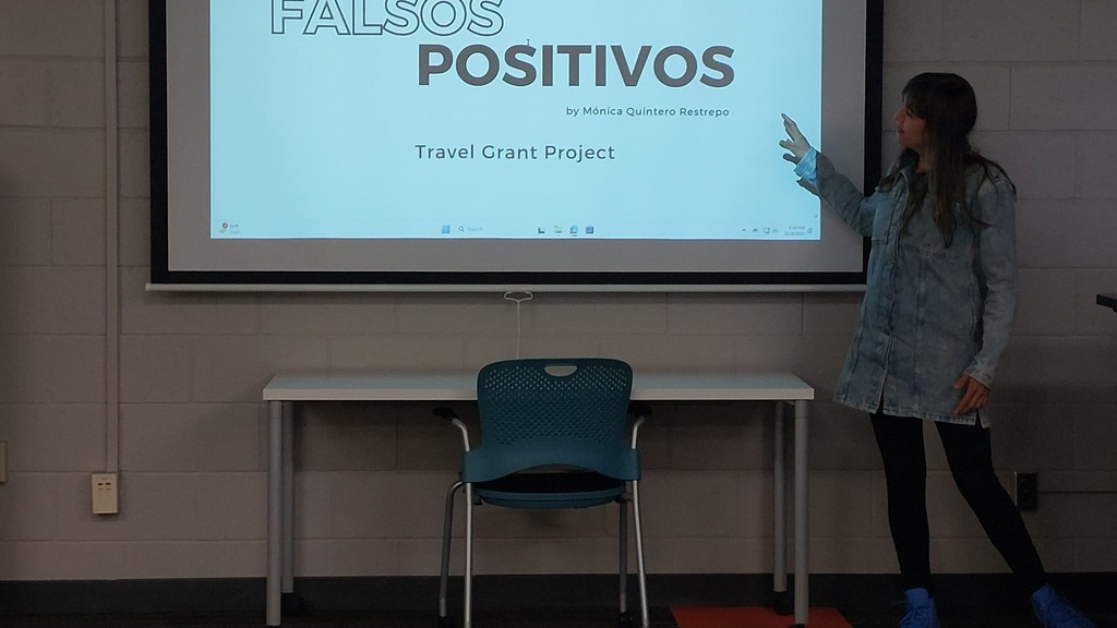 A woman presenting before a projection screen in a classroom